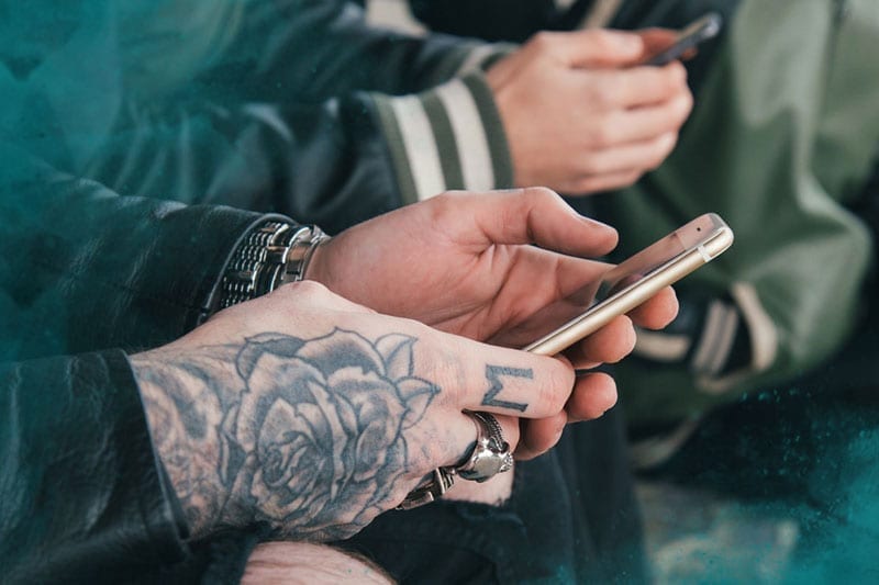 tattooed hands holding mobile phones
