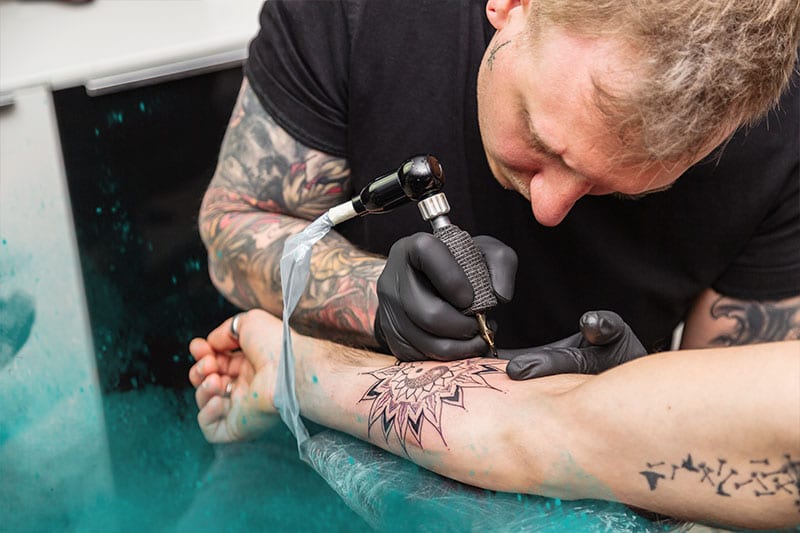 tattoo artist doing an arm tattoo